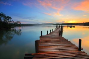 A dock stretching out onto a lake at sunset